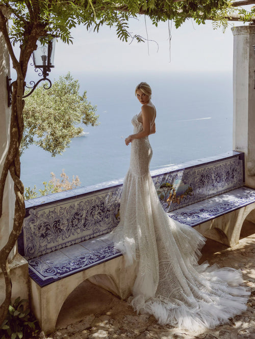 Shimmering mermaid wedding dress with intricate beadwork and a ruffled tulle train, bespoke bridal gown
