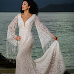 Bespoke boho mermaid lace wedding dress with deep plunging neckline and fringe bell sleeves, handcrafted bridal gown