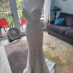Intricate beaded mermaid wedding dress with a plunging neckline and spaghetti straps, handcrafted bridal gown