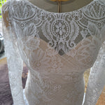 Intricate boat neck lace mermaid wedding dress with long sleeves and floral patterns, a bespoke handcrafted bridal gown